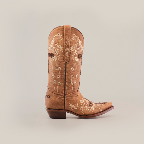 The Marga Cruz Fawn Crystals boot, handcrafted with intricate white and brown floral embroidery on premium leather, is showcased against a plain background. This tan cowboy boot features a snip toe and a low heel for an elegant look.