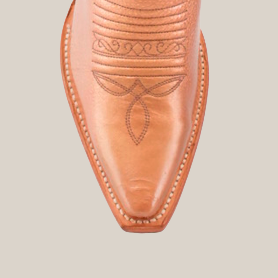 Close-up of the snip toe of a brown Taylor Rose Gold tall shaft cowboy boot, showcasing intricate swirl and leaf stitch patterns against a white background. The rose gold accents enhance its timeless elegance.