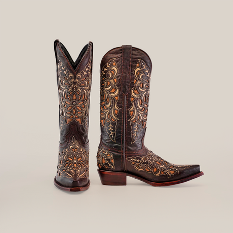 A handcrafted pair of Kiara Crystals Chocolate - Mid Shaft - Snip Toe cowboy boots features intricate floral embroidery. One boot stands upright, and the other lies on its side, displaying a curved heel against a plain white background that highlights this exquisite western footwear.