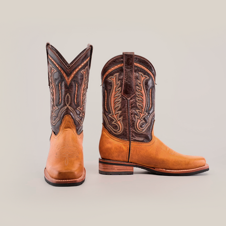 Discover the Cater Honey cowboy boots: crafted from premium cowhide leather with intricate patterns and detailed stitching. Featuring brown leather lowers, dark brown uppers, a slip-resistant sole, and designed to stand out on a plain white background.