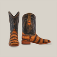 A pair of Gator Print Rustic Honey - Square Toe cowboy boots with black shafts and orange-brown leather flaunts a textured gator print. The left boot stands tall as the right tilts, highlighting its side and honey tones, all set against a white background.