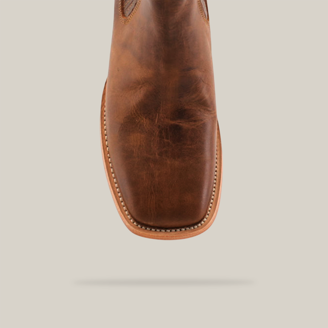 A close-up of a single Avejentado Honey Square Toe in rich brown leather showcases elegance and ruggedness. The polished finish and visible sole stitching reflect its cowboy style roots, all set against a plain white background.