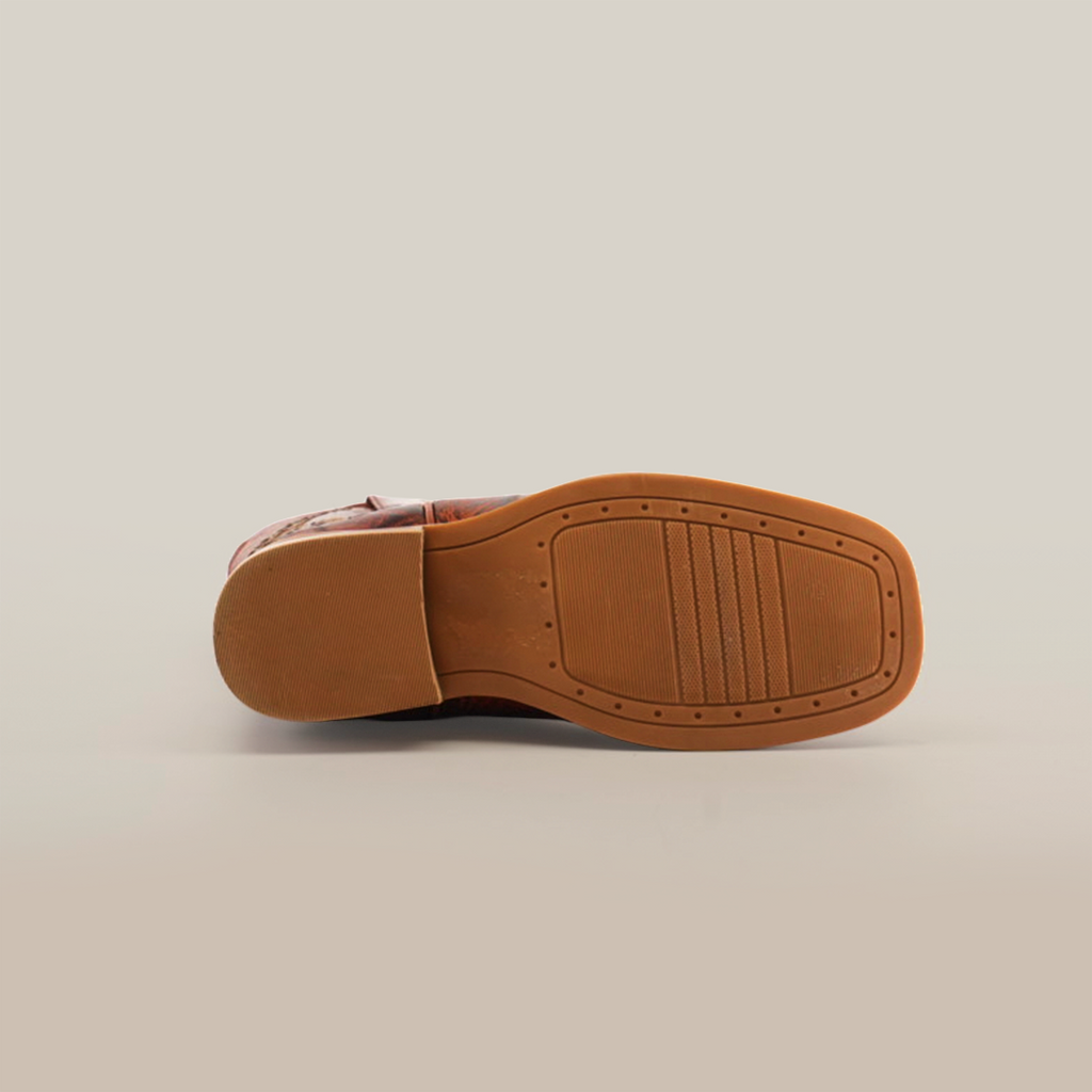 The Pirarucu Bass Print Cognac Square Toe shoe, crafted from premium leather, features a textured rubber sole and square heel. Its displayed sole-up against a plain white background.