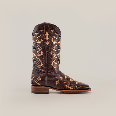 The Maya Brown - Short Shaft - Square Toe boot is crafted from premium leather, showcasing a brown cowboy style with intricate multicolored geometric embroidery, a square-toe design, side pull tabs, and a mid-height heel against a plain beige backdrop.