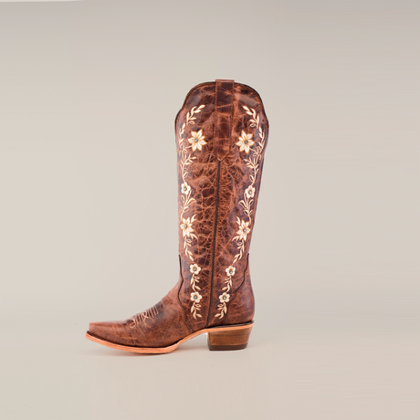 A single Mia Brown - Tall Shaft - Snip Toe boot made of premium leather with a pointed toe and medium-height heel. It features white floral embroidery, handcrafted elegance, and is showcased against a plain white background.