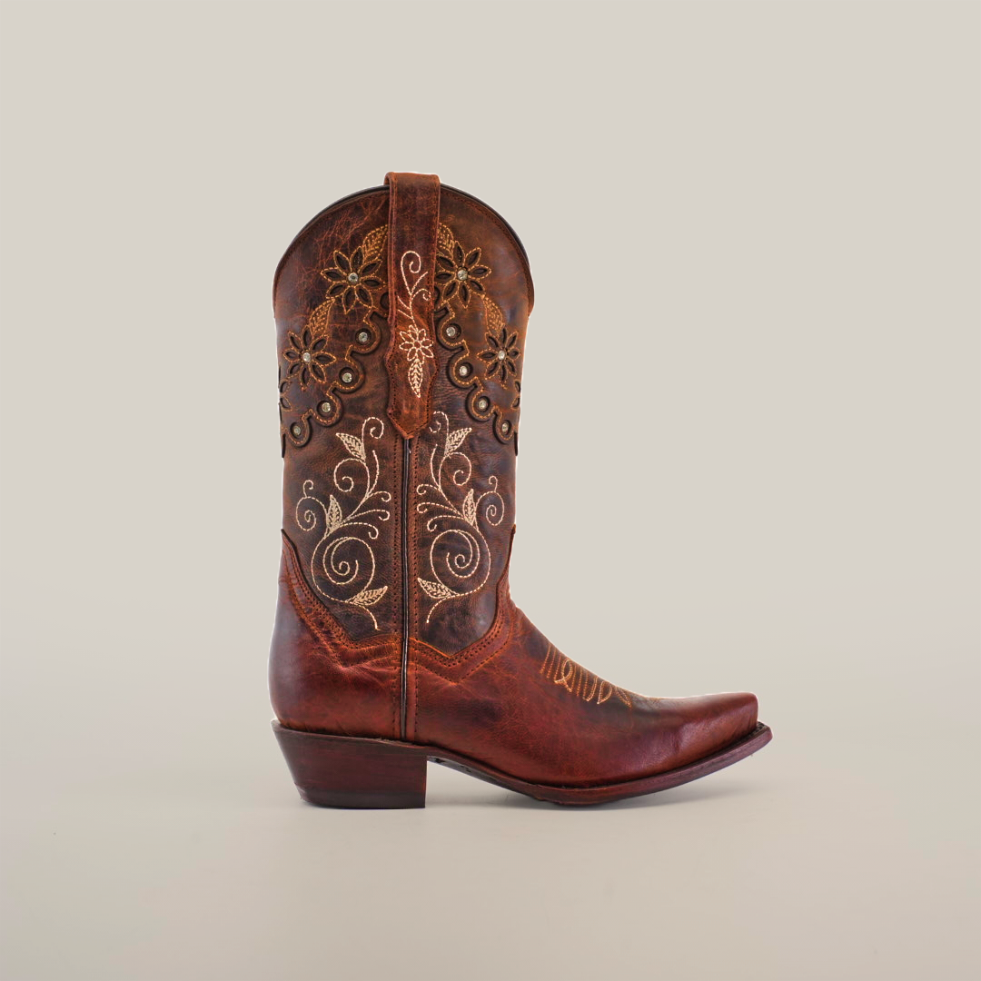 The Grecas Moka Crystals boot features artisanal craftsmanship with intricate floral embroidery and swirl patterns. Its short shaft and snip toe design exude handcrafted luxury, all set against a plain white background.