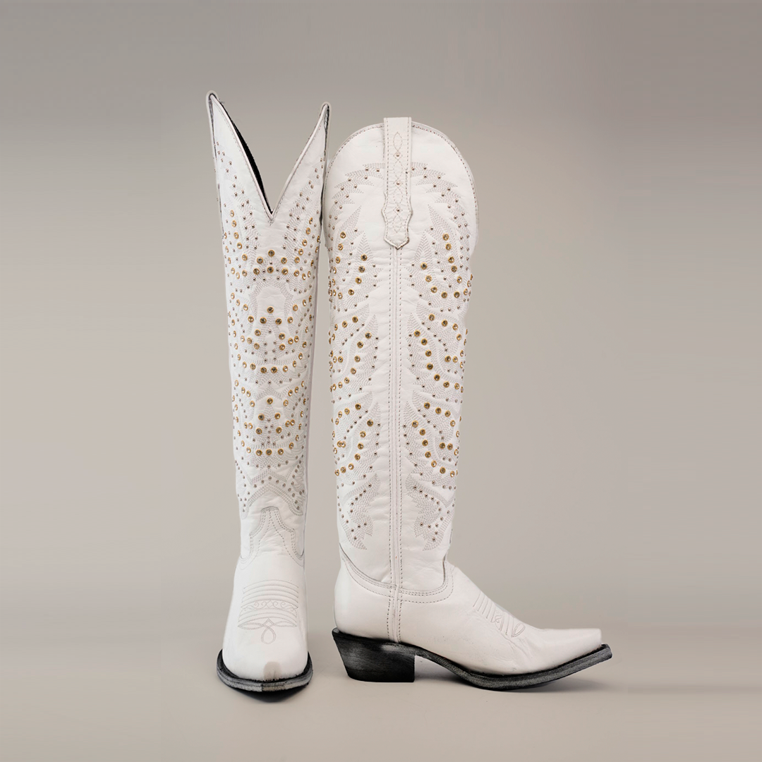 The Crystals Wings Frost White boots have a tall shaft and snip toe with intricate gold stud detailing, embroidery, and classic western-style stitching. The left boot is upright, while the right leans slightly.