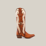 The Valentina Cogñac Tall Shaft boot in premium leather boasts intricate beige and metallic embroidery. It features a snip toe, low heel, and Western flair on a light gray backdrop, embodying elegance and unique craftsmanship.