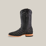 A single Exotic Piraruco Fish boot, matte black with a light brown sole, is shown against a white background. The square toe boot features intricate stitching and a side view highlighting its tall shaft.