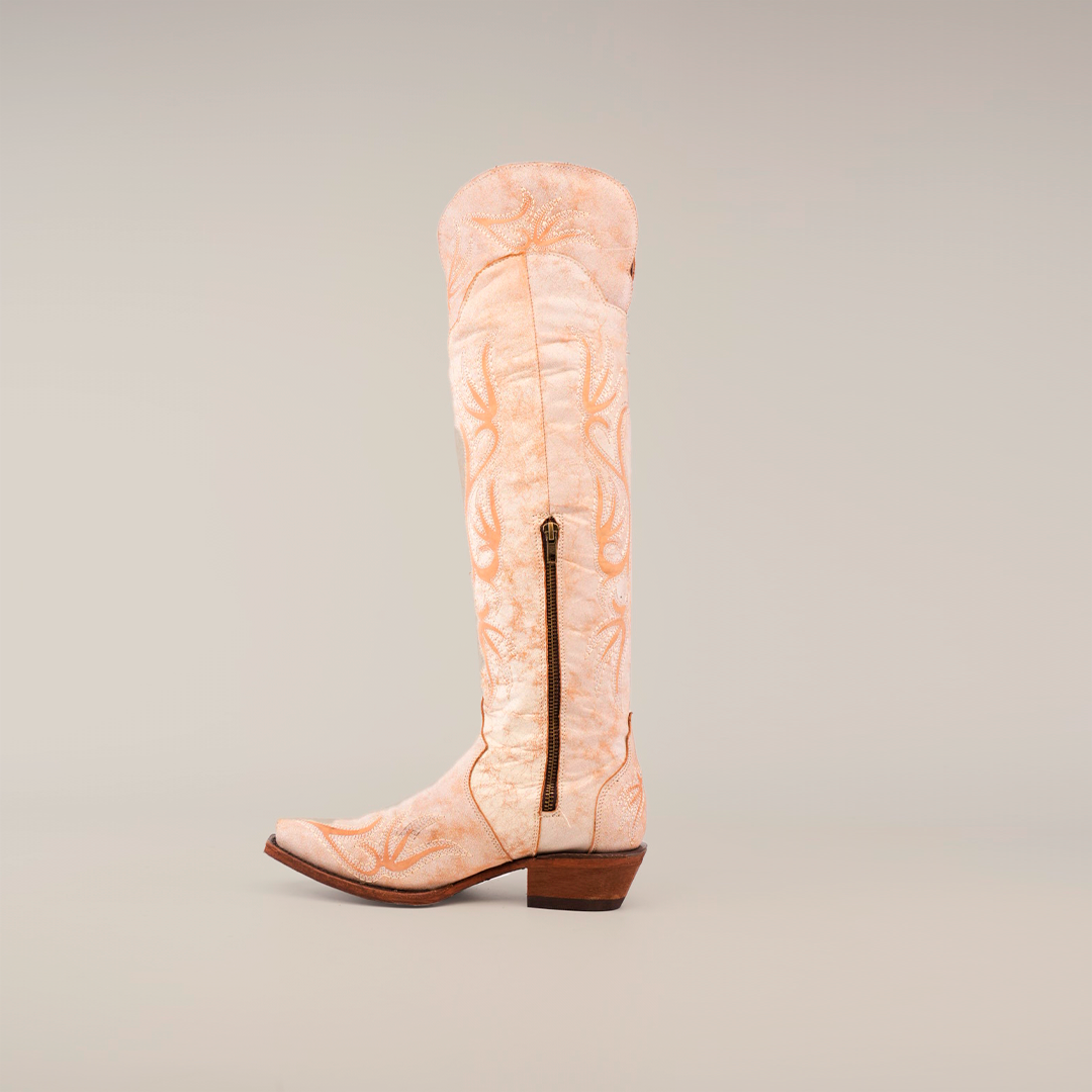 The Emma Alaska Orix-Tall Shaft in tan is a premium leather cowboy boot featuring a decorative embroidered pattern, side zipper, snip toe, and low heel. It is elegantly displayed against a plain white background.