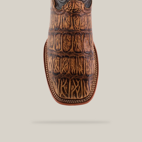 A close-up of the Gator Print Orix - Square Toe boot reveals its handcrafted, western-style design with a textured Gator Print pattern on the toe, intricate stitching along the edges, and a square toe. The cowhide leather showcases various brown shades for a rustic look.