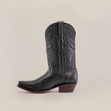 The Plane Jane Black- Short Shaft - Snip Toe boot, made from premium leather, features detailed stitching and a pointed toe. Set against a white backdrop, it has a low wooden heel and decorative shaft patterns, exuding Western artistry.