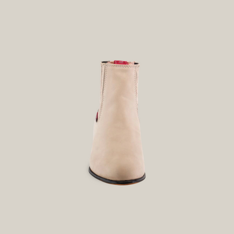 A Prime Suede Pearl Round Toe boot is showcased on a white background. This handcrafted, light beige suede ankle boot features stitching details and minimal branding, viewed from the front with a slightly rounded toe.