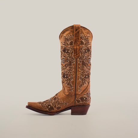 The Alamo Camel Crystals boot, with a snip toe and mid shaft, is crafted from brown leather. It features intricate floral embroidery, artisanal craftsmanship, and a low angled heel against a plain white background.