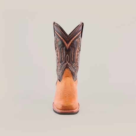 The Cater Honey features a single cowboy boot crafted from premium cowhide leather, boasting a brown lower section and a dark upper with intricate stitching. Its Western patterns offer a textured, colorful contrast atop the slip-resistant sole.