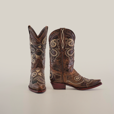 Etnia Tabaco boots flaunt exquisite leather craftsmanship with white stitching and paisley patterns. One womens snip toe boot stands upright, while the other is angled, all set against a plain white background.