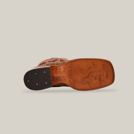 The image features the underside of the American Alligator Print Rustic Orix cowboy boot in brown with a square toe. A leather sole shows an embossed logo and visible black heel tacks on a plain white background.