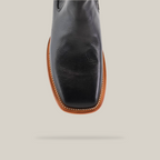 A detailed look at the Napa Black Square Toe leather cowboy boot reveals its handcrafted square toe design, tan welted sole, and edge stitching. Set against a plain white background to highlight its elegance.