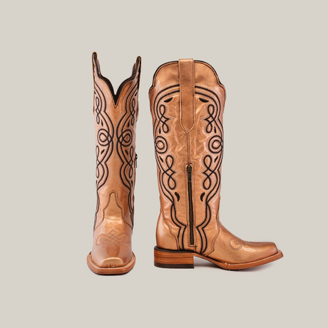 A pair of Eden Rose Gold boots with black embroidery, one upright and the other showing its side with a zipper. These stunning boots feature a pointed toe and low heel, perfect for making a bold statement.