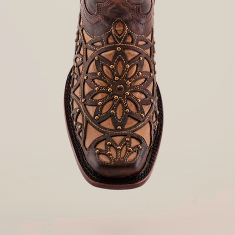 Close-up of handcrafted Vitralli Studs Tabaco boots highlighting intricate floral and geometric patterns on the toe, blending dark and light brown tones. Crafted from premium leather with decorative stitching, these mid-shaft boots feature a narrow square-shaped toe design.