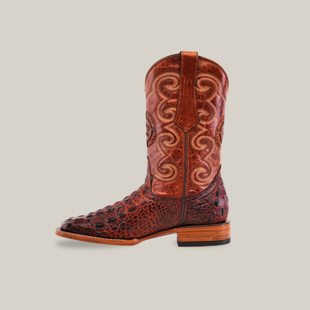 The Morelet Crocodile Print Cogñac boot features a square toe, intricate leather patterns, and decorative stitching. Made from premium cowhide leather with both textured and smooth surfaces, it includes a sturdy wooden heel and pull strap for style and durability.